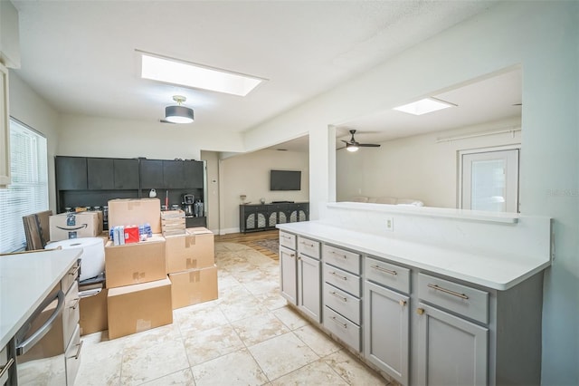 interior space featuring a skylight, light countertops, gray cabinetry, and open floor plan