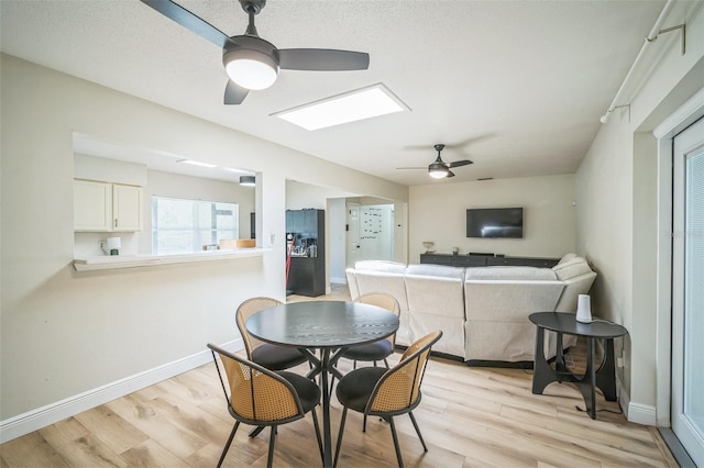 dining room with light wood-type flooring, a ceiling fan, and baseboards