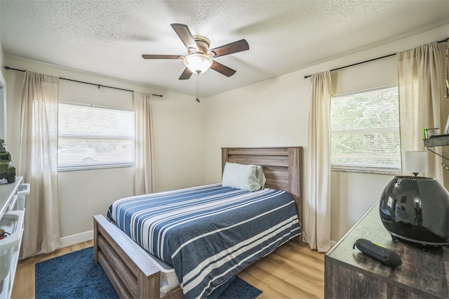 bedroom featuring a textured ceiling, multiple windows, and wood finished floors