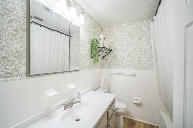 full bathroom featuring vanity, a wainscoted wall, and wallpapered walls