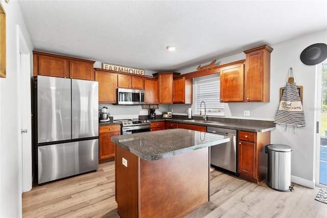 1555 Seminole Run Rd, Osteen, FL 32764 - kitchen featuring a kitchen island, dark countertops, a sink, light wood finished floors, and stainless steel appliances