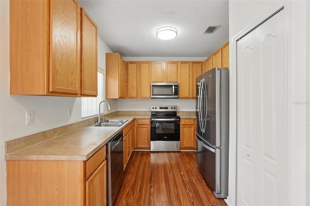 kitchen featuring a sink, light countertops, stainless steel appliances, visible vents, and dark wood-style floors
