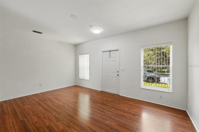 unfurnished room featuring baseboards, wood finished floors, and visible vents
