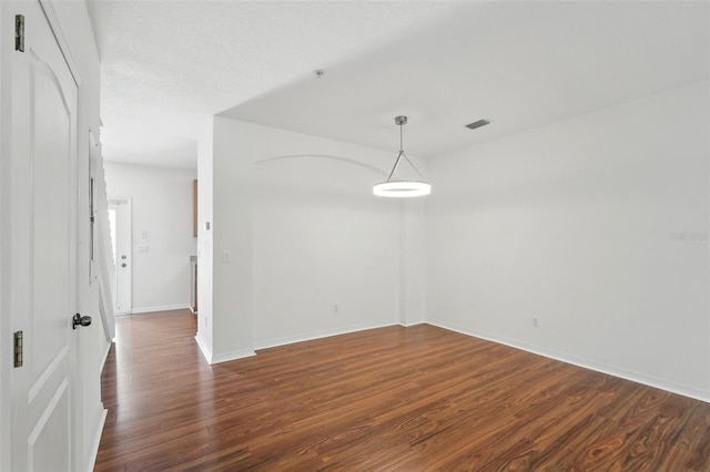 interior space with baseboards, visible vents, and dark wood-type flooring