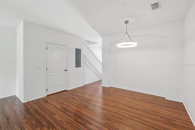 unfurnished dining area featuring baseboards, wood finished floors, visible vents, stairway, and electric panel