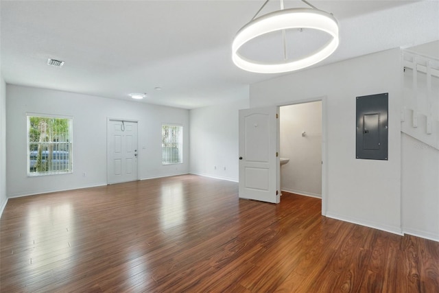 unfurnished living room featuring visible vents, plenty of natural light, wood finished floors, and electric panel