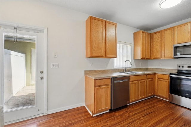kitchen featuring baseboards, dark wood-style floors, light countertops, a sink, and stainless steel appliances