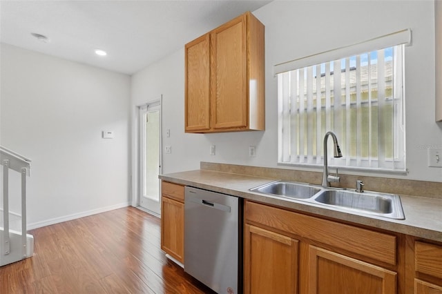 kitchen with a sink, light countertops, baseboards, wood finished floors, and stainless steel dishwasher