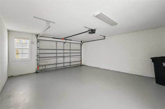 garage with a garage door opener and concrete block wall