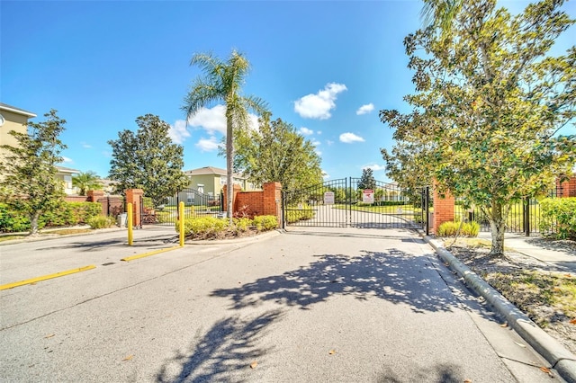 view of street with a gated entry, a gate, and curbs