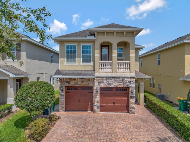mediterranean / spanish-style home with an attached garage, decorative driveway, stucco siding, and stone siding