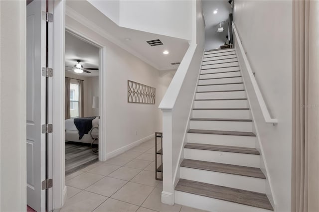 stairway featuring crown molding, ceiling fan, tile patterned flooring, baseboards, and visible vents