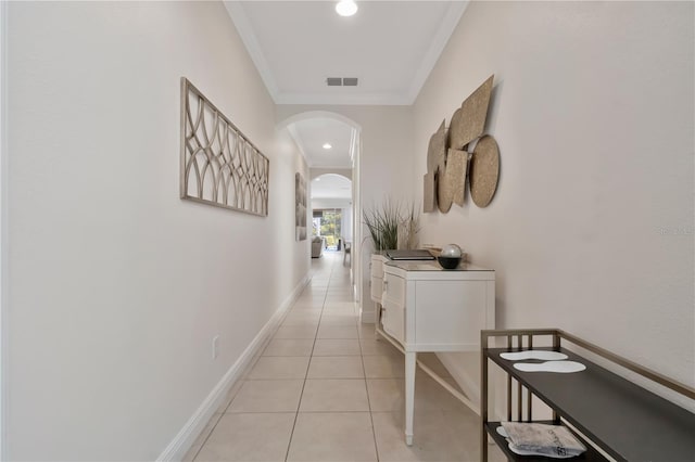 corridor featuring arched walkways, baseboards, light tile patterned floors, visible vents, and ornamental molding