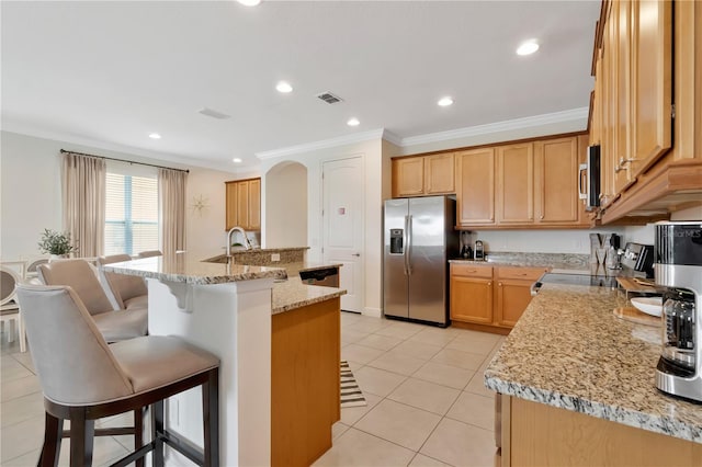 kitchen with crown molding, light tile patterned flooring, an island with sink, a kitchen bar, and stainless steel appliances