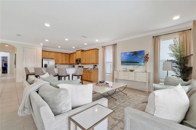 living area featuring crown molding, arched walkways, and a healthy amount of sunlight