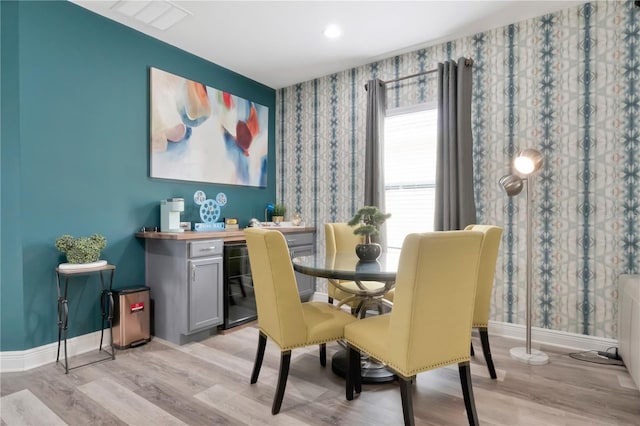 dining area with baseboards, light wood-type flooring, and wallpapered walls