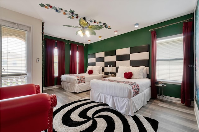 bedroom with multiple windows, an accent wall, and light wood-style floors