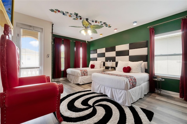 bedroom with an accent wall and wood finished floors