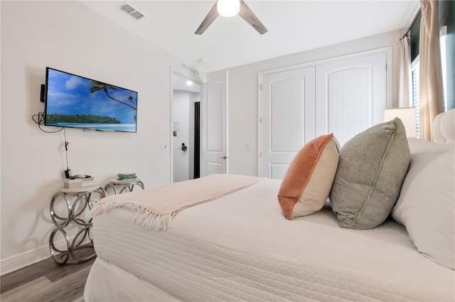 bedroom with a ceiling fan, visible vents, wood finished floors, baseboards, and a closet