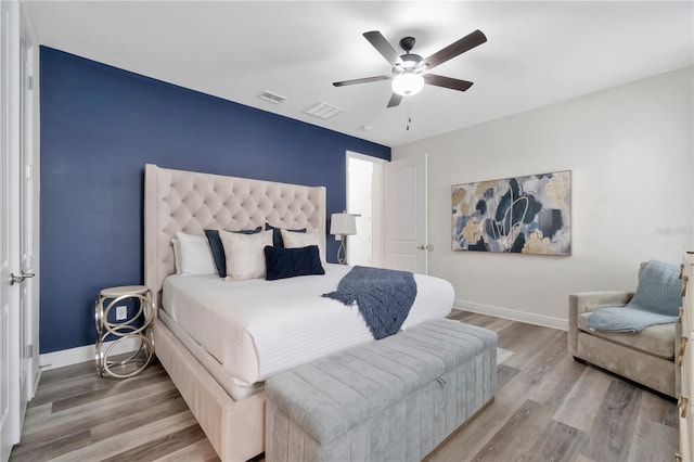 bedroom with baseboards, a ceiling fan, wood finished floors, and visible vents