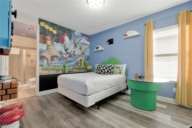 bedroom with baseboards, wood finished floors, and ensuite bath