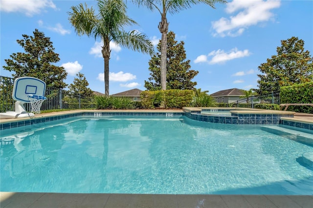 view of swimming pool featuring a water slide, a pool with connected hot tub, and fence