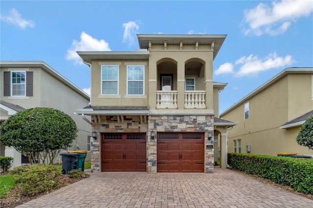 view of front of property with stucco siding, decorative driveway, stone siding, and a garage