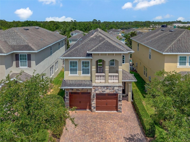 view of front facade featuring stucco siding, an attached garage, decorative driveway, and stone siding