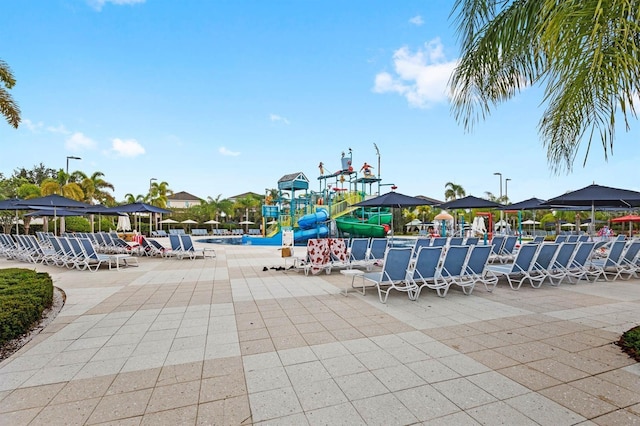view of pool with a water slide, a water play area, and a patio