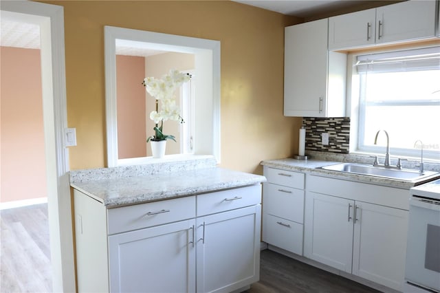 kitchen with white cabinets, electric range, a sink, tasteful backsplash, and dark wood-type flooring