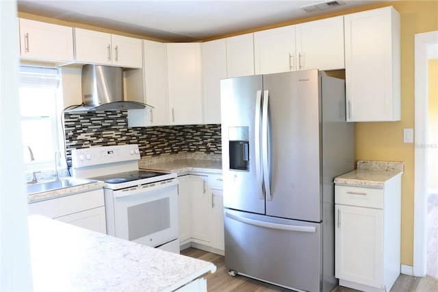 kitchen featuring a sink, light wood finished floors, stainless steel fridge with ice dispenser, wall chimney exhaust hood, and electric stove