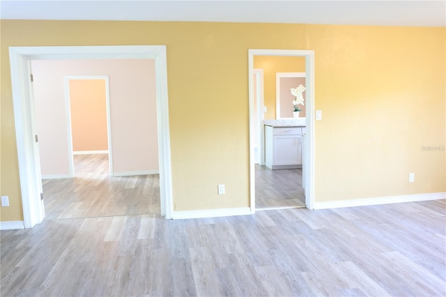 spare room with baseboards and light wood-style flooring