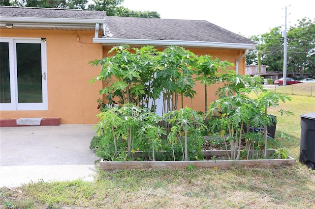 view of side of property featuring stucco siding, a yard, and a garden