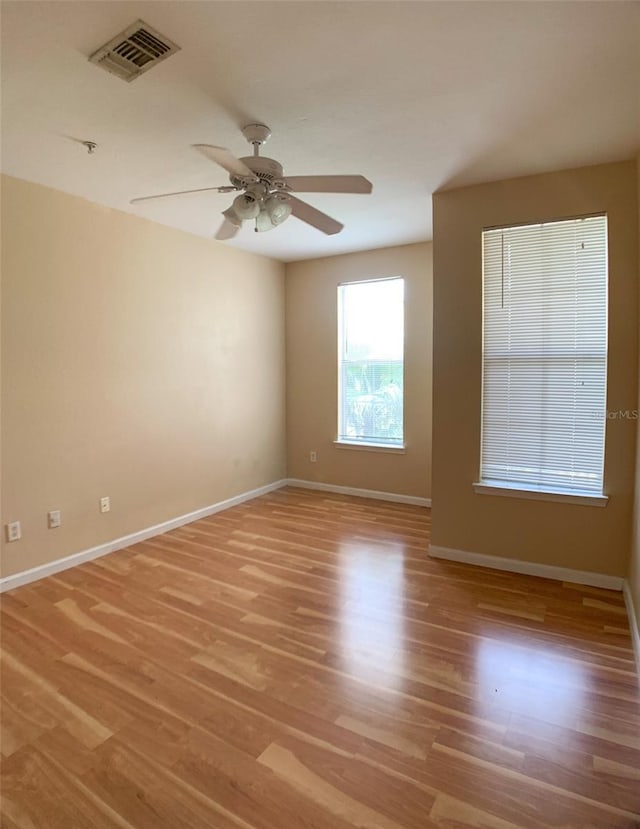 unfurnished room with visible vents, a ceiling fan, light wood-style flooring, and baseboards