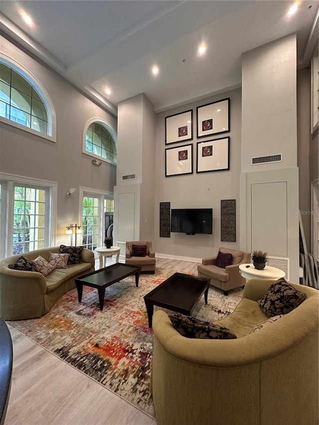 living room with a high ceiling, recessed lighting, and wood finished floors
