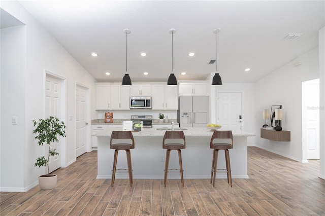 kitchen with white cabinets, stainless steel appliances, a spacious island, and light wood-type flooring