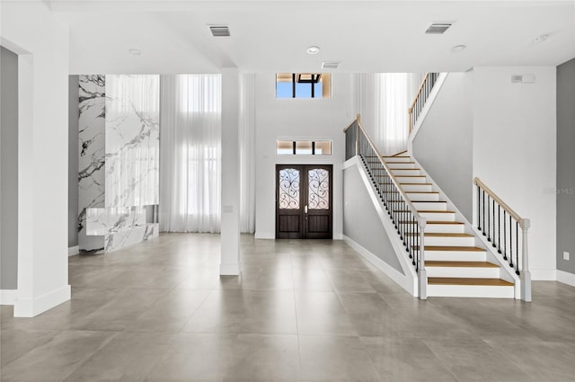entryway with visible vents, baseboards, a towering ceiling, and stairs