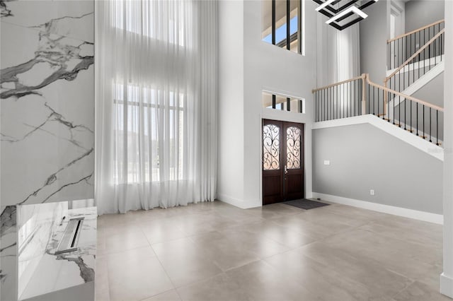 foyer featuring stairway, french doors, plenty of natural light, and a towering ceiling
