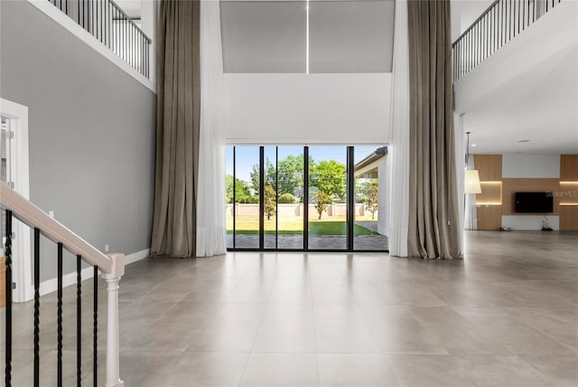 unfurnished living room with tile patterned floors, a towering ceiling, and stairs