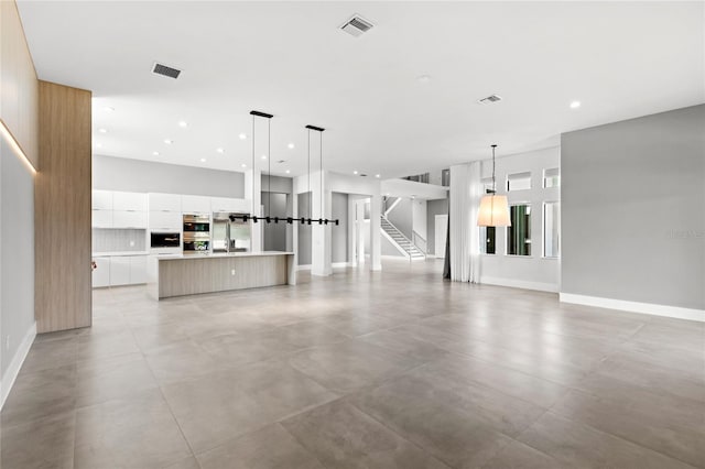 unfurnished living room featuring baseboards, recessed lighting, stairway, and visible vents