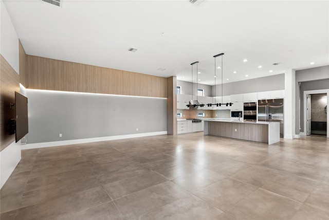 unfurnished living room with recessed lighting, visible vents, and a high ceiling