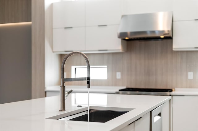 kitchen featuring exhaust hood, modern cabinets, a sink, light countertops, and white cabinets