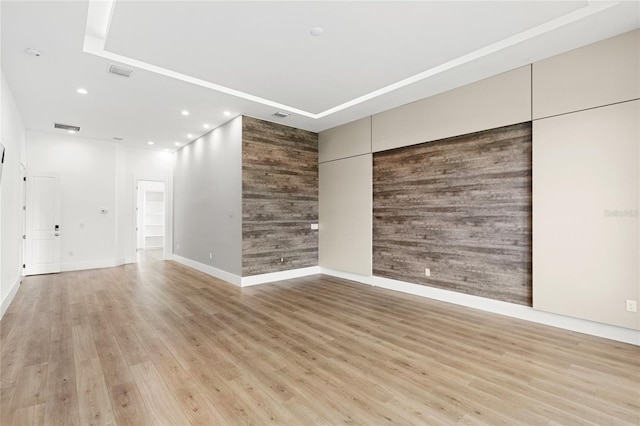 empty room featuring light wood-type flooring, wood walls, baseboards, and recessed lighting