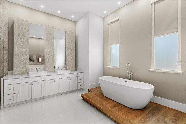 bathroom featuring a soaking tub, recessed lighting, baseboards, and vanity