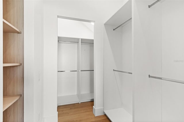 walk in closet with wood finished floors