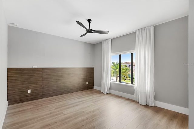 spare room featuring light wood-type flooring, baseboards, and ceiling fan