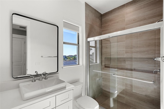 bathroom featuring vanity, toilet, a shower stall, and visible vents