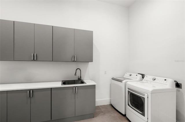 washroom with a sink, cabinet space, baseboards, and independent washer and dryer