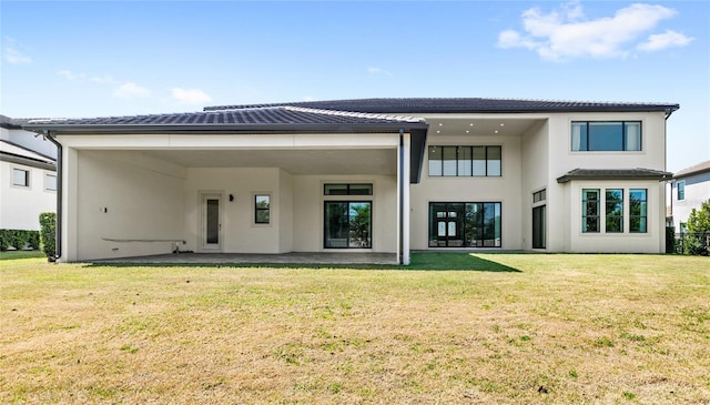 rear view of property with a tiled roof, stucco siding, and a lawn