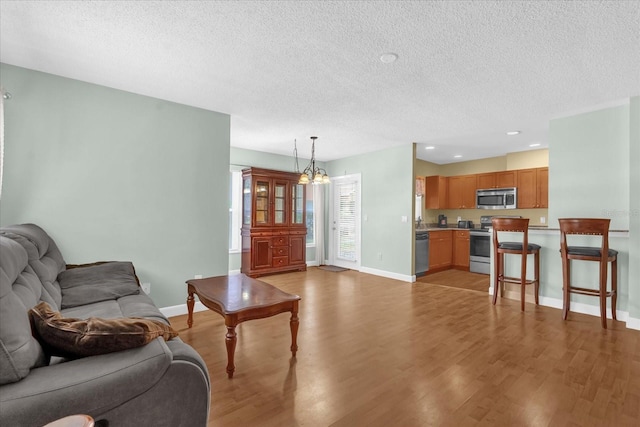 living area featuring a textured ceiling, baseboards, and light wood-type flooring
